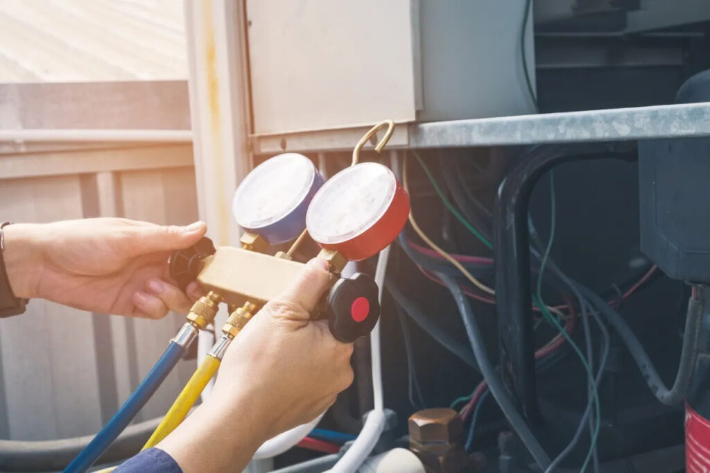 Technician holding HVAC gauge set for maintenance and repair, emphasizing home warranty services for HVAC systems.